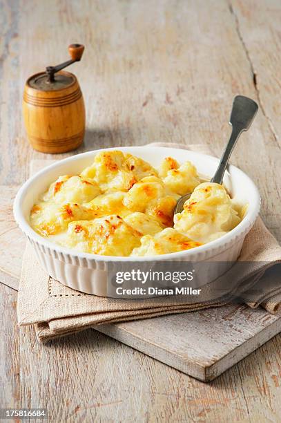 cauliflower cheese in large bowl with spoon and wooden pepper grinder - cauliflower cheese stock-fotos und bilder