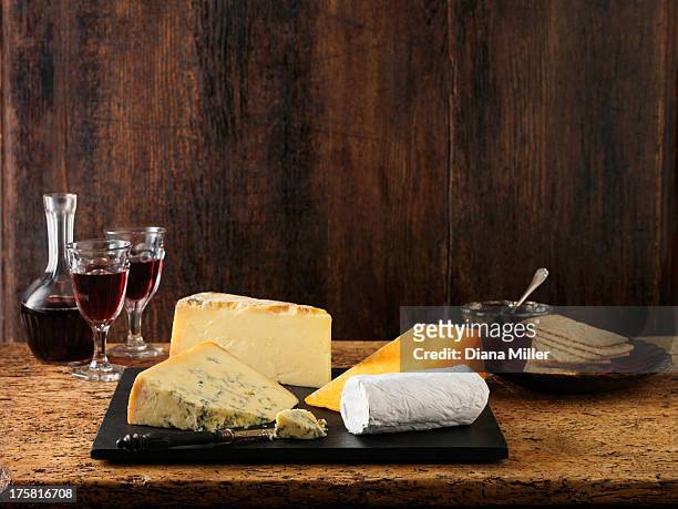 speciality christmas cheeseboard selection. stilton, goats cheese, red leicester and cheddar with red wine and crackers - cheese plate stock-fotos und bilder