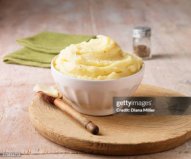 ultimate mashed potato with black pepper in white faceted bowl with wooden spoon - stampen stockfoto's en -beelden