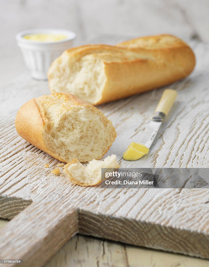 White baguette with butter on white wooden board