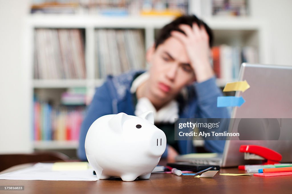 Piggy bank with young man worrying in background