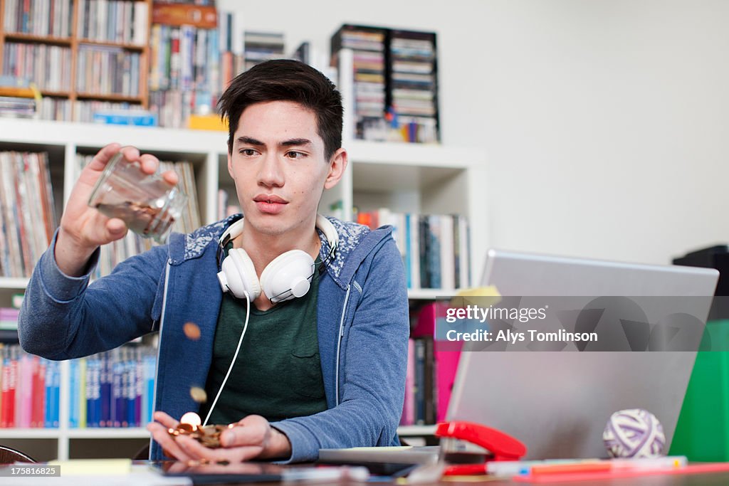 Young man emptying jar of coins