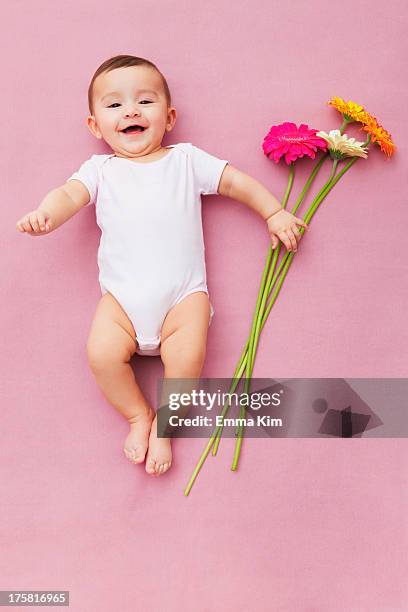 baby girl with gerbera flowers - baby lachen natur stock-fotos und bilder