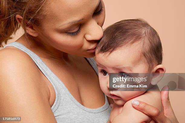 mother kissing her baby girl - studio kiss stock pictures, royalty-free photos & images