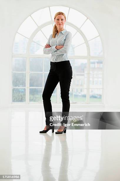 businesswoman standing in sparse white room - business women pants stock-fotos und bilder