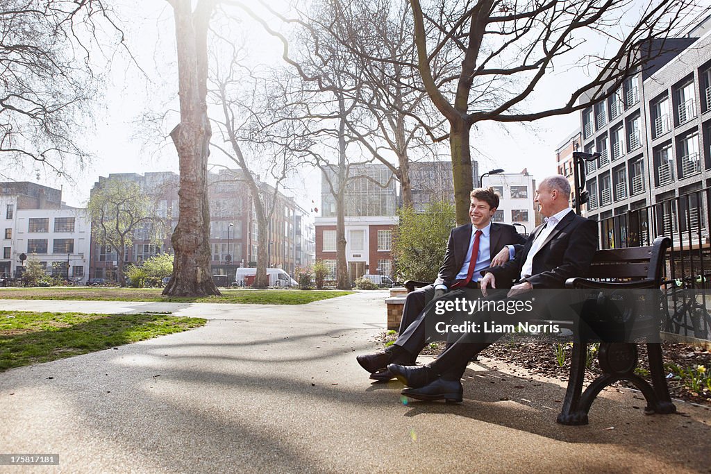 Two businessmen sitting on park bench