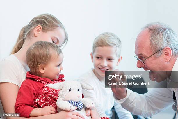 child on sister's lap being examined by doctor - girl tongue doctor stockfoto's en -beelden