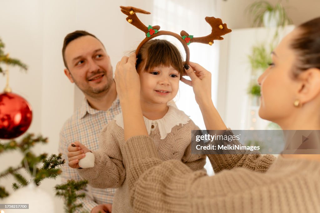 Family pithing them selfs reindeer headbands and celebrating Christmas together at home