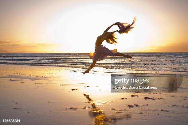 young woman dancing on sunlit beach - danseuse photos et images de collection