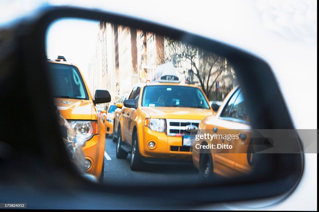 Queue of yellow cabs viewed through wing mirror, New York City, USA