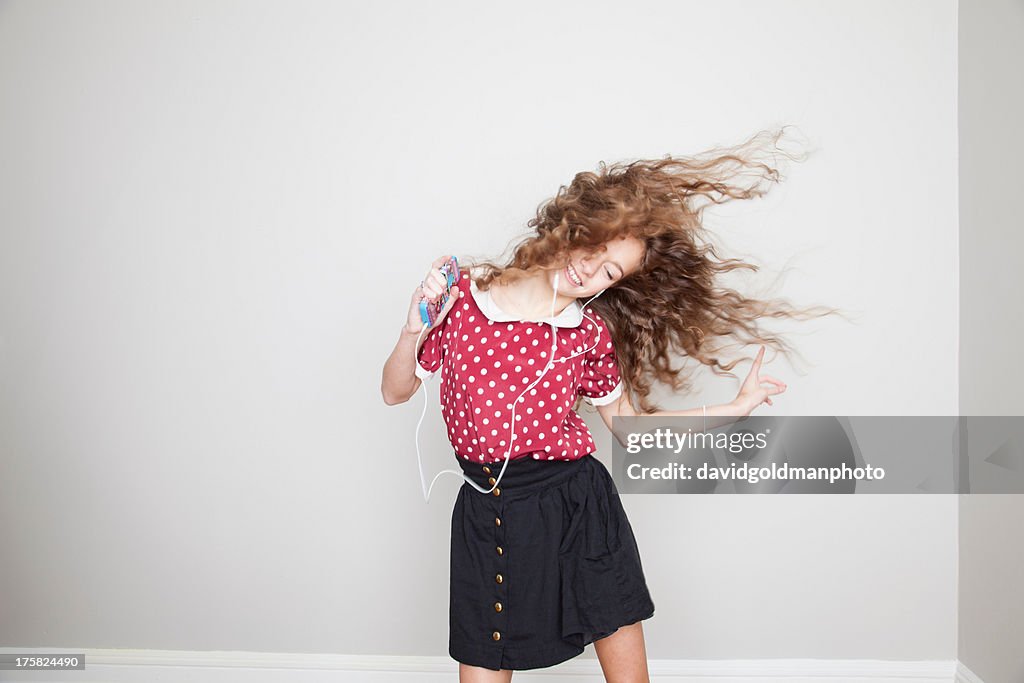Girl wearing headphones, dancing and holding mp3 player