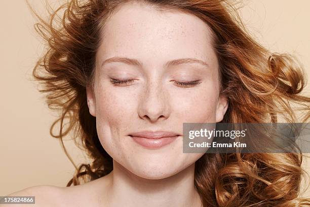 studio shot of young woman with curly red hair, eyes closed - eyes closed stock-fotos und bilder