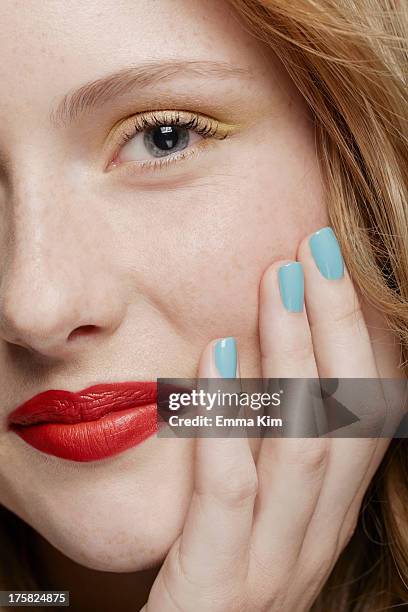 cropped shot of young woman with curly red hair wearing make up, hand on chin - red nail polish stockfoto's en -beelden