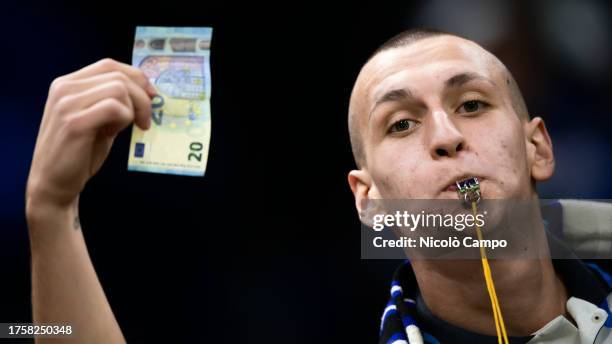 Internazionale fan blows a whistle and waves a twenty euro note towards Romelu Lukaku of AS Roma during warm up prior to the Serie A football match...