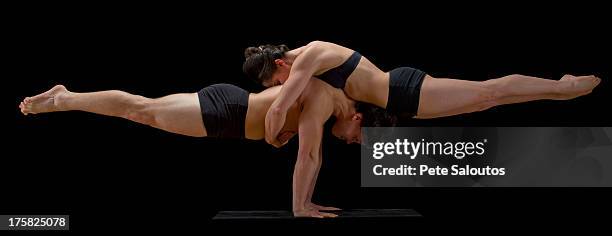 mid adult dancers performing together in front of black background - akrobatik stock-fotos und bilder