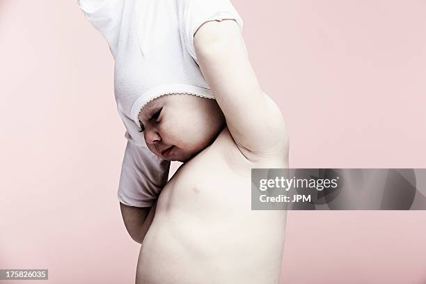 portrait of baby girl taking off top - entkleiden stock-fotos und bilder