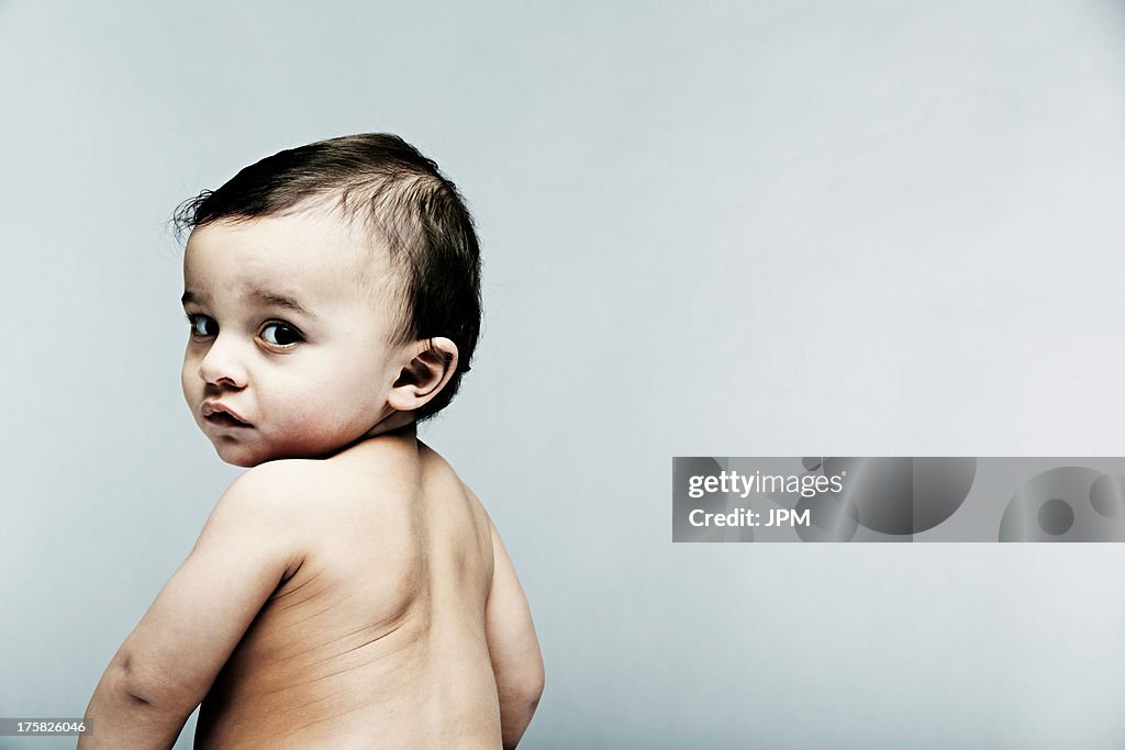 Portrait of baby boy looking over shoulder at camera