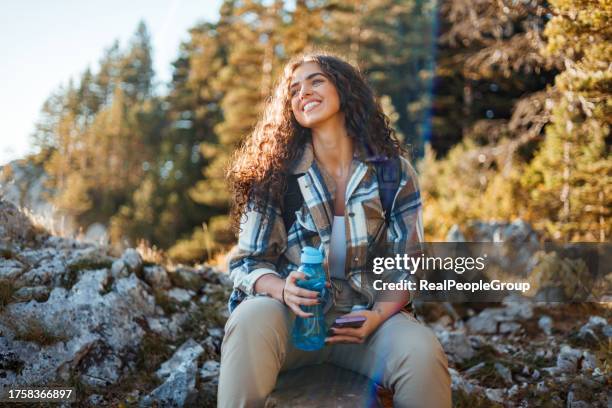 mountain hiker consults phone during trek - travel real people stockfoto's en -beelden