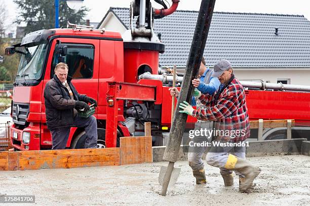 europe, germany, rhineland-palatinate, construction workers filling concrete for foundation and man holding remote control - betonmischmaschine stock-fotos und bilder