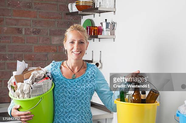 germany, cologne, mature woman carrying buckets with household garbage in kitchen - daily bucket foto e immagini stock