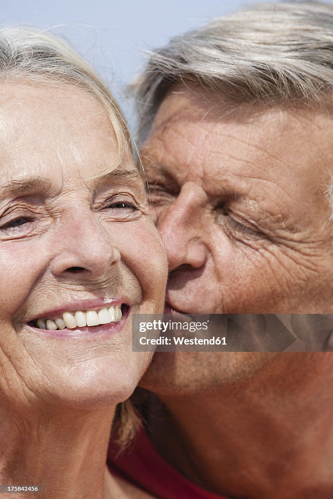 Spain, Senior man kissing to woman, close up