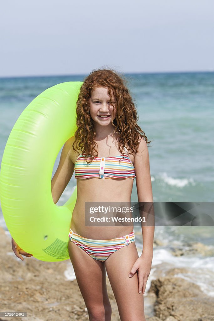 Spain, Girl with swim ring on beach, smiling