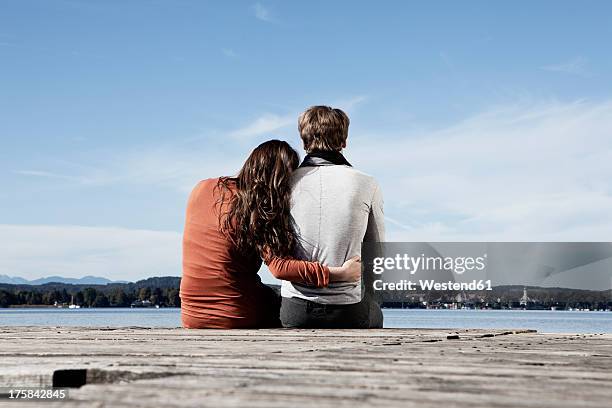 germany, bavaria, couple sitting on jetty at lake starnberg - head on shoulder stock pictures, royalty-free photos & images