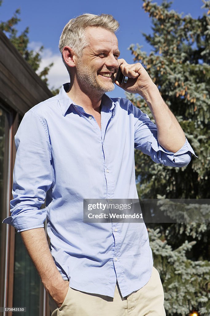 Germany, Berlin, Mature man talking on mobile phone, smiling