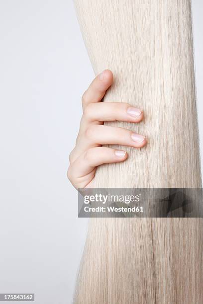 human hand holding blond hair against white background, close up - hand in hair ストックフォトと画像