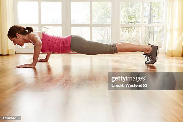 germany, duesseldorf, mature woman doing push ups at home - flexiones fotografías e imágenes de stock