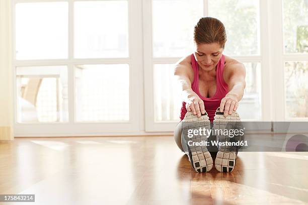 germany, duesseldorf, mature woman exercising at home - zehenspitzen berühren stock-fotos und bilder