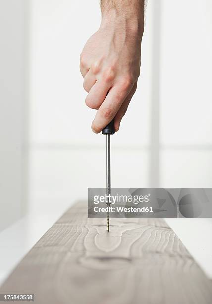 human hand driving screw into wooden board - schraubenzieher stock-fotos und bilder