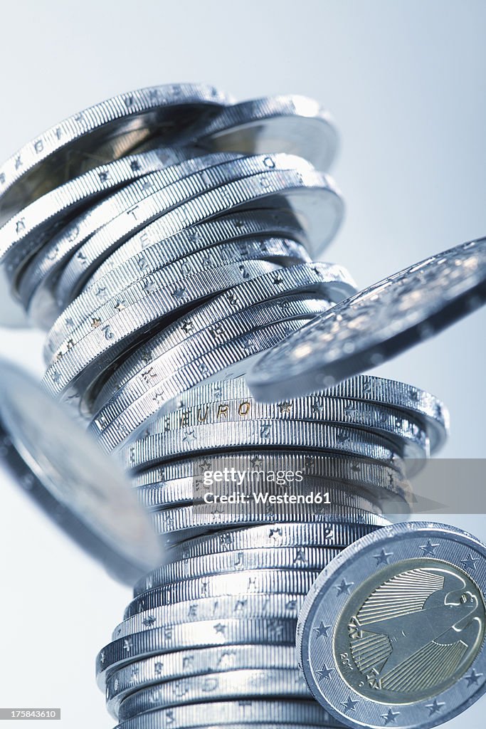 Euro coins collapsing against white background, close up