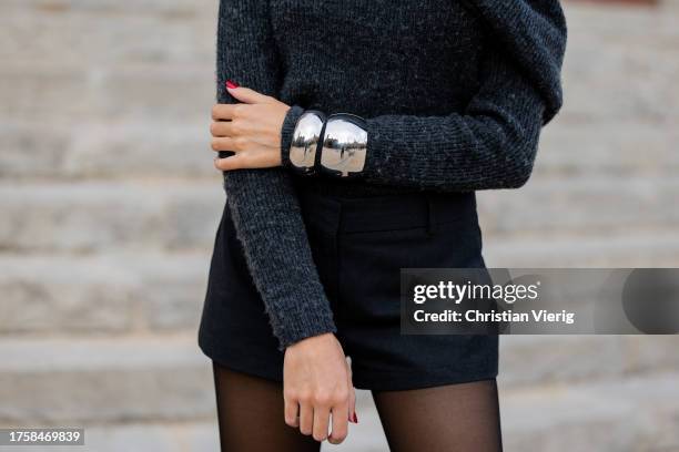 Guest wears grey wrapped jumper, black shorts, sheer tights, silver bracelets at day 3 of 080 Barcelona Fashion 2023 at Recinte Modernista de Sant...