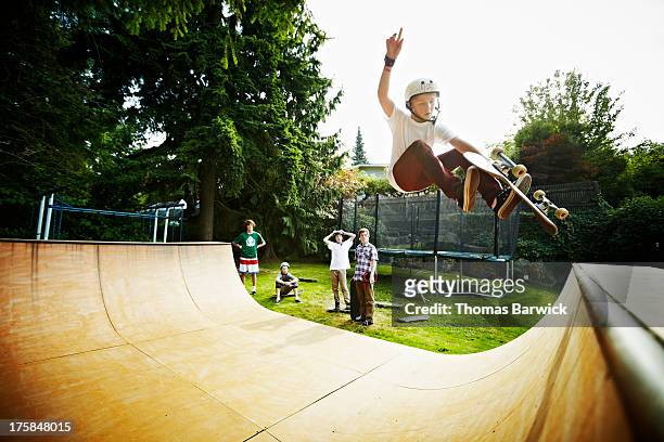 young male skateboarder in mid air on halfpipe - halfpipe stockfoto's en -beelden