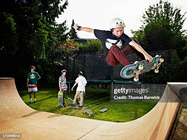 young male skateboarder in mid air on halfpipe - boy skatepark stock-fotos und bilder