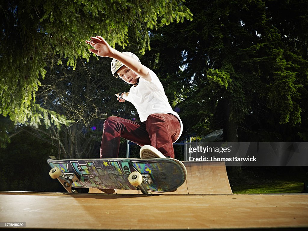 Young skateboarder sliding along rail of halfpipe