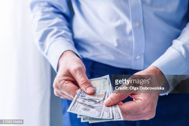 close-up view of a man holding u.s. dollar banknotes in front of him - true crime stock pictures, royalty-free photos & images
