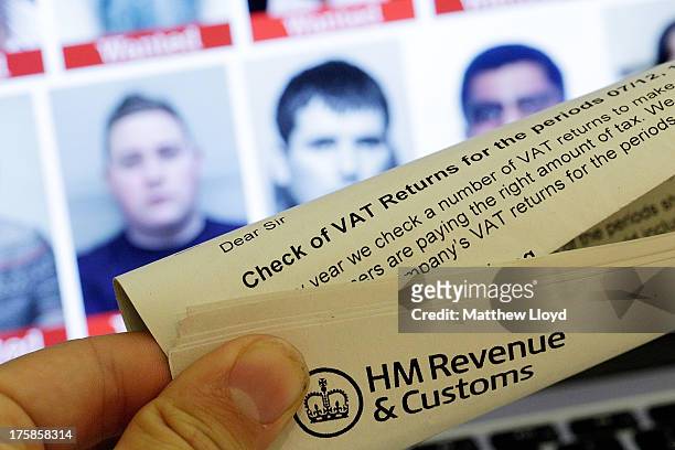 In this photo illustration a tax document is seen in front of a laptop screen showing the HMRC Flickr feed with the faces of their most wanted tax...