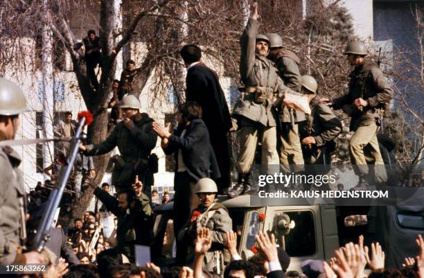 Picture released on January 15, 1979 shows army soldiers decorating their weapons with flowers as they fraternize with people in a Tehran street....