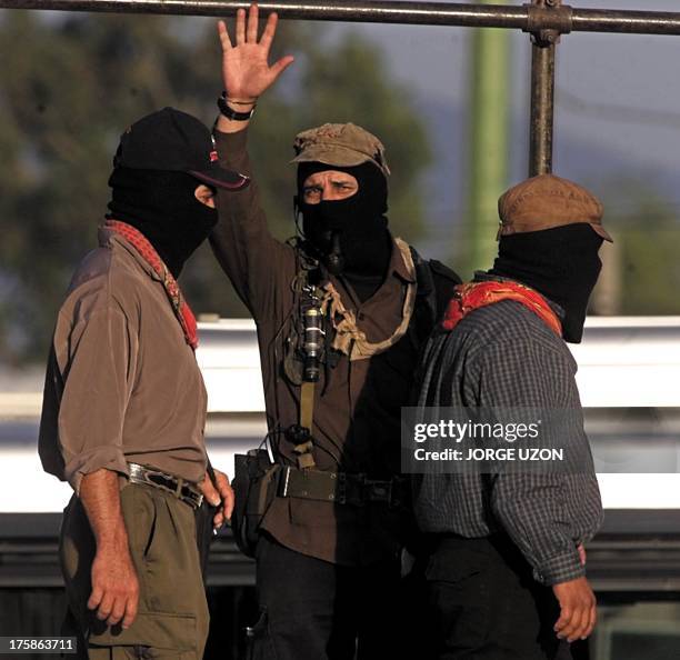Subcommander Marcos waves, between two other Zapatista commanders, after a rally in front of the Legislative Palace in Mexico City 22 March 2001, one...