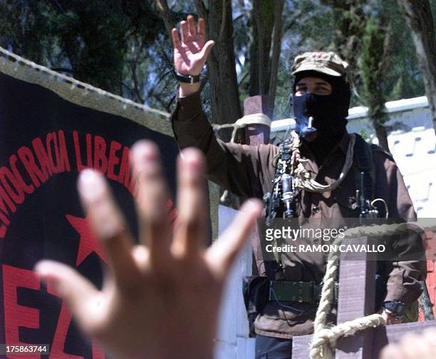 Mexican rebel leader "Subcomandante Marcos" waves to a massive crowd upon his arrival 11 March 2001 in Xochimilco, a suburb of Mexico City. The...