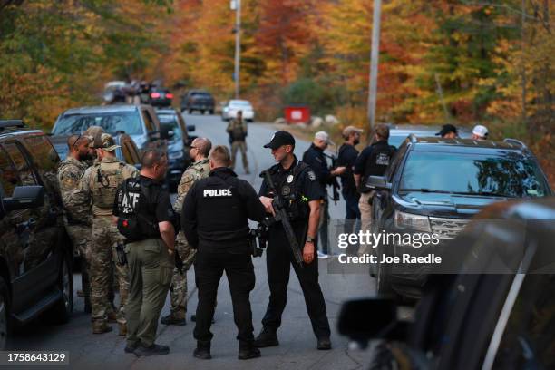 Law enforcement officials gather in the road leading to the home of the suspect being sought in connection with two mass shootings on October 26,...