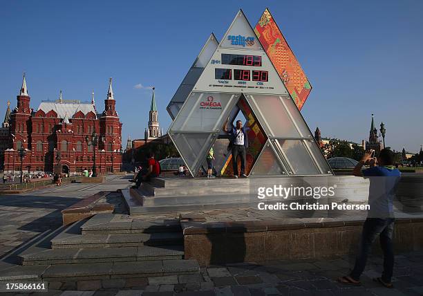 Tourists pose for photos underneath a countdown clock for the 2016 Sochi Winter Olympic Games ahead of the 14th IAAF World Championships at on August...