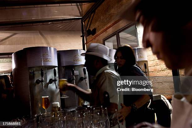 Bartender pours glasses of Cia. De Bebidas das Americas Bohemia brand beer at a restored Bohemia brewery in Petropolis, Brazil, Sunday, Aug. 4, 2013....