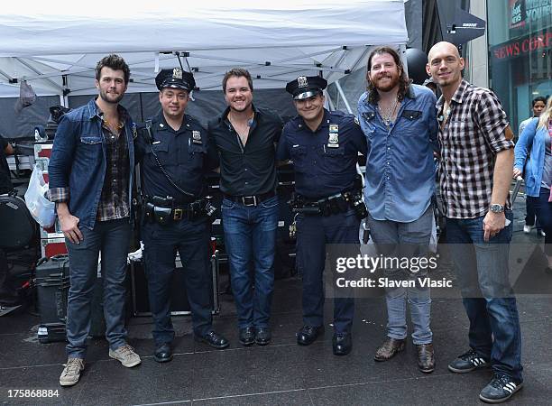 Eli Young Band members Chris Thompson, Mike Eli, James Young and Jon Jones pose with NYPD officers backstage at 'FOX & Friends' All American Concert...