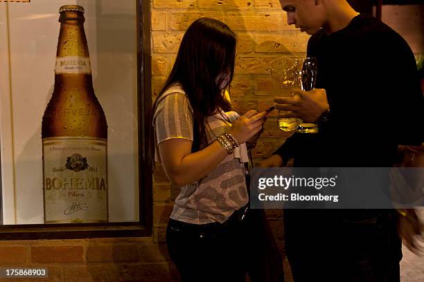 Sign for Cia. De Bebidas das Americas Bohemia brand beer hangs on a wall near patrons at a restored Bohemia brewery in Petropolis, Brazil, Sunday,...