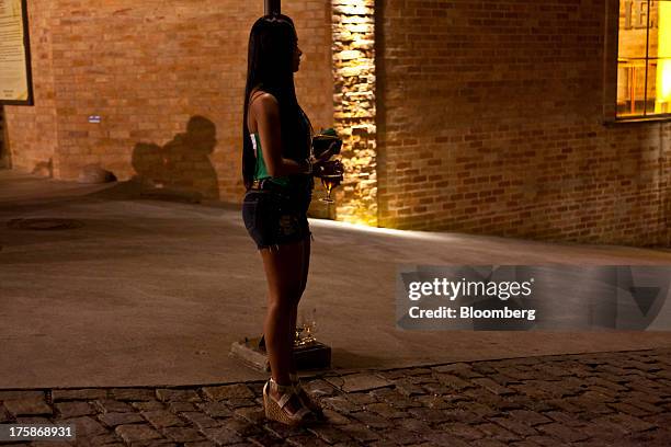 Woman holds glasses of Bebidas das Americas Bohemia brand beer outside a restored Bohemia brewery in Petropolis, Brazil, Sunday, Aug. 4, 2013....