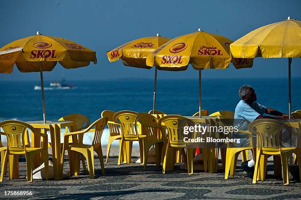 Tables and umbrellas displaying the logo for Cia. De Bebidas das Americass Skol brand beer sit near Ipanema beach in Rio de Janeiro, Brazil, on...