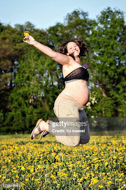 pregnant woman jumping high - person holding flowers with high energy stock-fotos und bilder